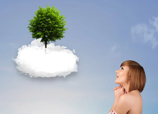 Junges Mädchen zeigt auf einen grünen Baum auf einer weißen Wolke — Stockfoto