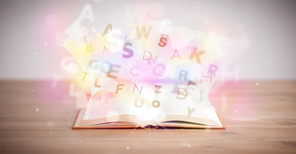 Άνοιγμα βιβλίου με λαμπερά γράμματα σε φόντο τσιμέντου — Φωτογραφία Αρχείου