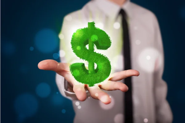 Young businessman presenting green glowing dollar sign — Stock Photo, Image