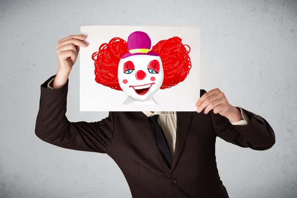 Biznesmen trzymając karton z clown na to przed h — Zdjęcie stockowe