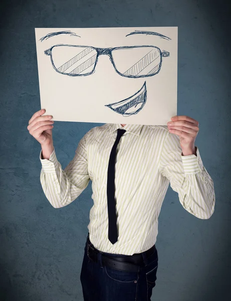 Empresario sosteniendo un papel con la cara sonriente delante de su hea — Foto de Stock