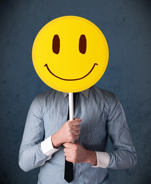 Empresario sosteniendo un emoticono sonriente — Foto de Stock