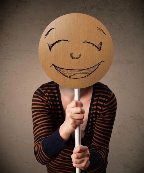 Young woman holding a smiley face board — Stock Photo, Image