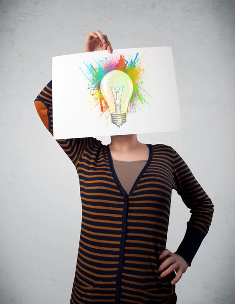 Woman holding a cardboard with paint splashes and lightbulb in f — Stock Photo, Image