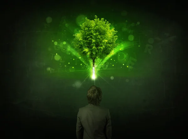 Hombre de negocios haciendo gestos frente a un árbol brillante — Foto de Stock