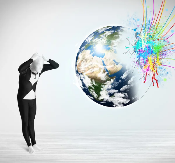 Funny man in body suit looking at colorful splatter earth — Stock Photo, Image