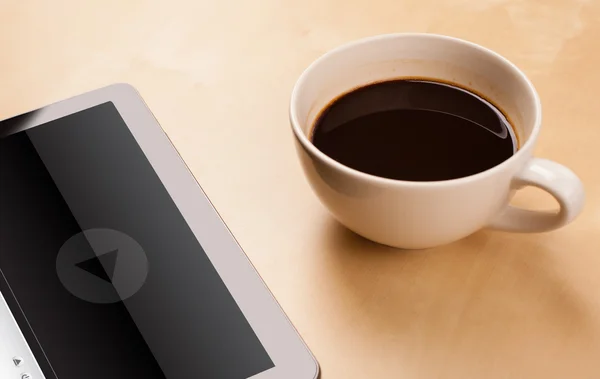 Tablet pc showing media player on screen with a cup of coffee on — Stock Photo, Image