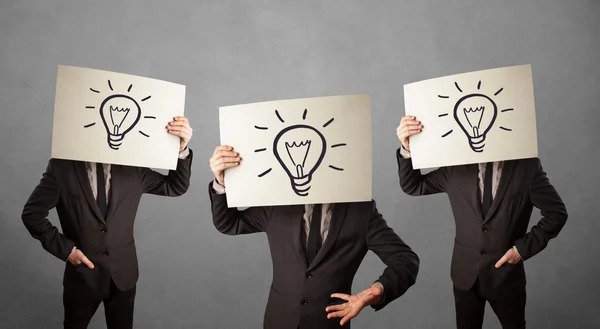Men in suit gesturing with sketched lightbulbs on cardboard — Stock Photo, Image