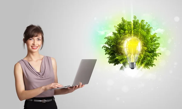 Jong meisje presenteren idee gloeilamp met groene boom — Stockfoto