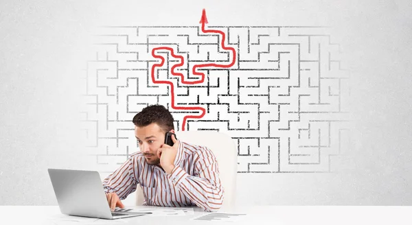 Business man at desk with labyrinth and arrow — Stock Photo, Image