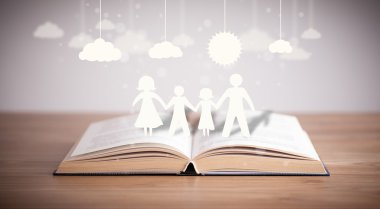 Ailenin karton figürleri açık bir kitabın üzerinde.