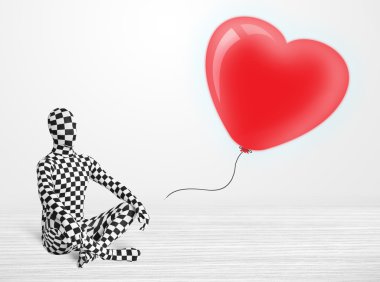 Morpsuit giyip balon şeklinde bir kalbe bakan yakışıklı bir adam.