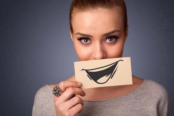 Happy cute girl holding paper with funny smiley drawing — Stock Photo, Image