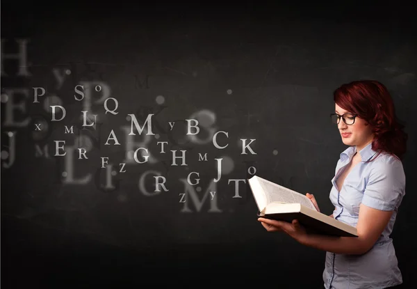 Junge Frau liest ein Buch mit Buchstaben des Alphabets — Stockfoto