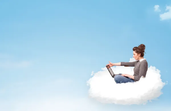 Mujer joven con portátil sentado en la nube con espacio de copia — Foto de Stock