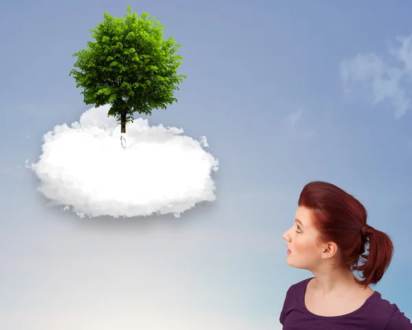 Молодая девушка указывает на зеленое дерево на вершине белого облака — стоковое фото