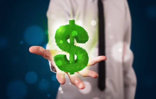Young businessman presenting green glowing dollar sign — Stock Photo, Image