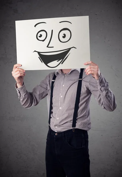 Empresário segurando um papelão com rosto sorridente na frente — Fotografia de Stock