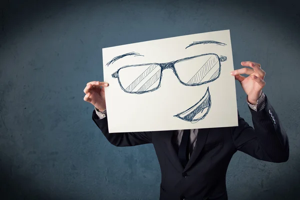 Empresario sosteniendo un papel con la cara sonriente delante de su hea — Foto de Stock