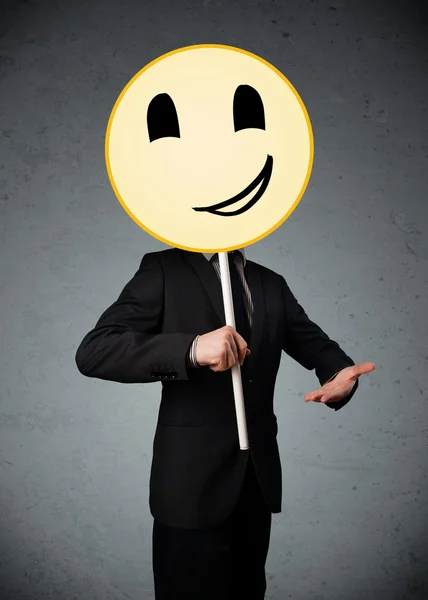 Empresario sosteniendo un emoticono sonriente — Foto de Stock