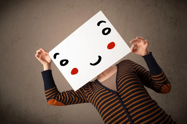 Mulher segurando um papelão com um rosto sorridente — Fotografia de Stock