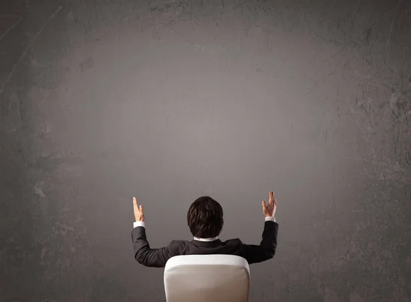 Businessman sitting in front of a wall with copy space — Stock Photo, Image