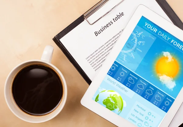 Tablet pc showing weather forecast on screen with a cup of coffe — Stock Photo, Image