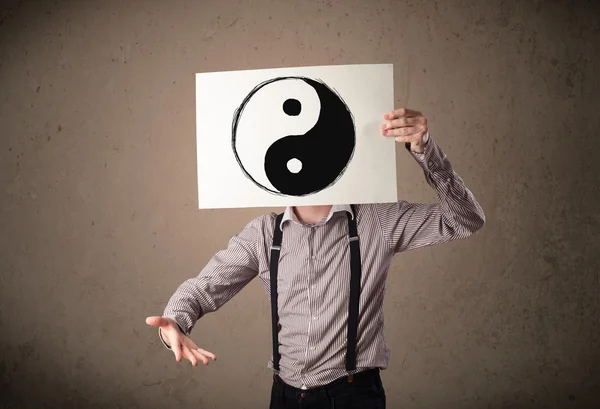 Businessman holding a paper with a yin-yang on it in front of hi — Stock Photo, Image