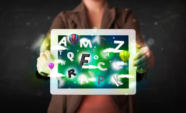 Young person showing tablet with abstract letters and sky — Stock Photo, Image
