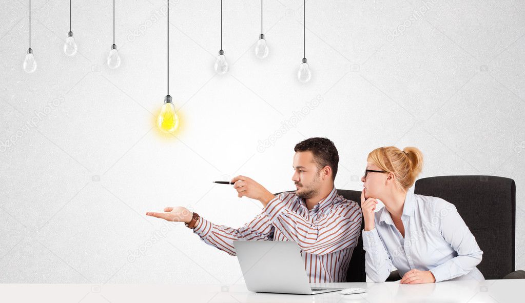 Business man and woman sitting at table with idea light bulbs