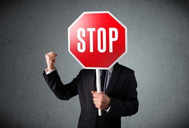 İşadamı elinde dur levhası tutuyor.