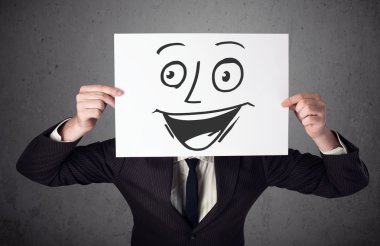 empresario sosteniendo una cartulina con cara sonriente en él en frente
