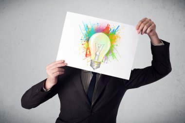 boya sıçraması ve lightbul ile bir karton tutan işadamı