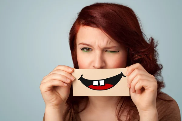 Happy pretty woman holding card with funny smiley — Stock Photo, Image