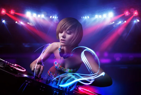 Disc jockey girl playing music with light beam effects on stage — Stock Photo, Image