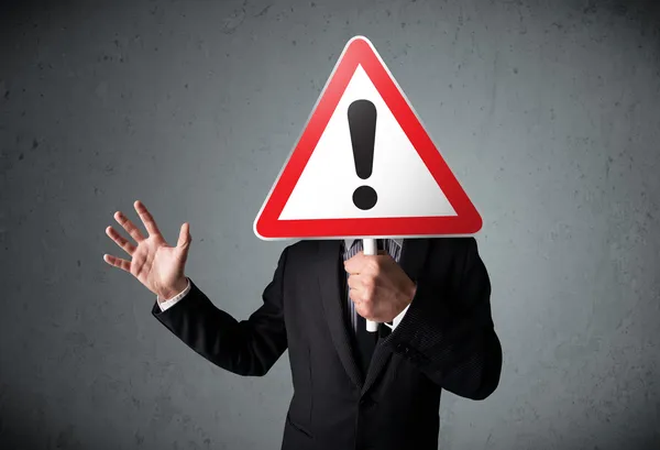 Businessman holding an exclamation road sign — Stock Photo, Image