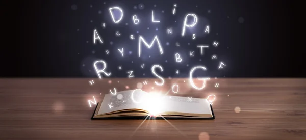 Libro abierto con letras brillantes volando — Foto de Stock