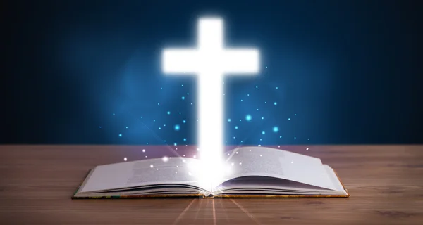 Open holy bible with glowing cross in the middle — Stock Photo, Image