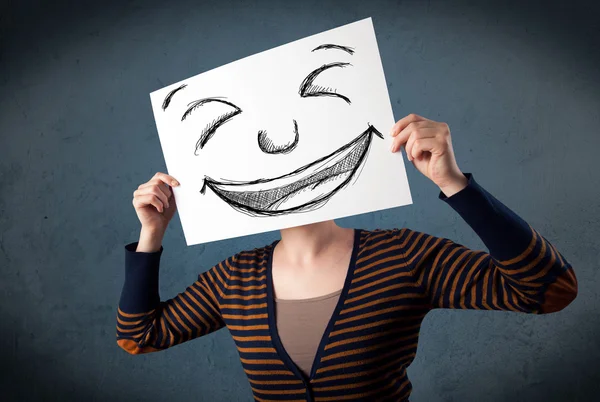 Mujer con la cara sonriente dibujada en un papel delante de su cabeza — Foto de Stock