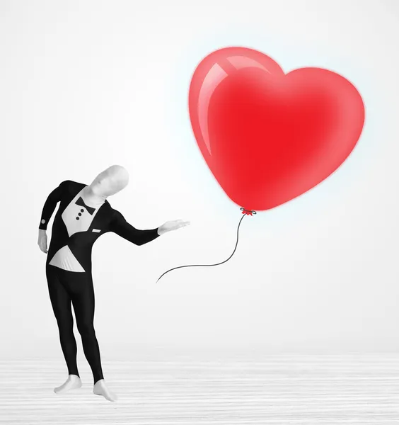 Lindo tipo en traje de cuerpo morpsuit mirando un corazón en forma de globo — Foto de Stock