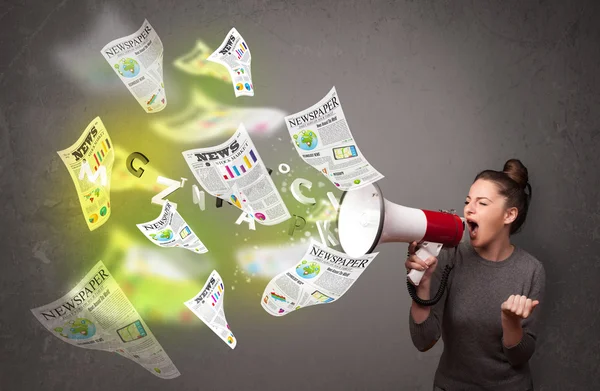 Girl yelling into loudspeaker and newspapers fly out — Stock Photo, Image