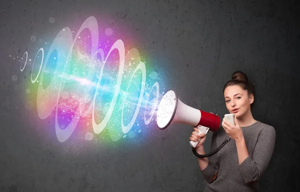 Young girl yells into a loudspeaker and colorful energy beam com — Stock Photo, Image