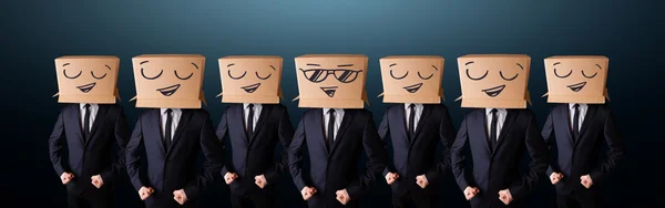 Handsome men in suit gesturing with drawn smiley faces on box — Stock Photo, Image