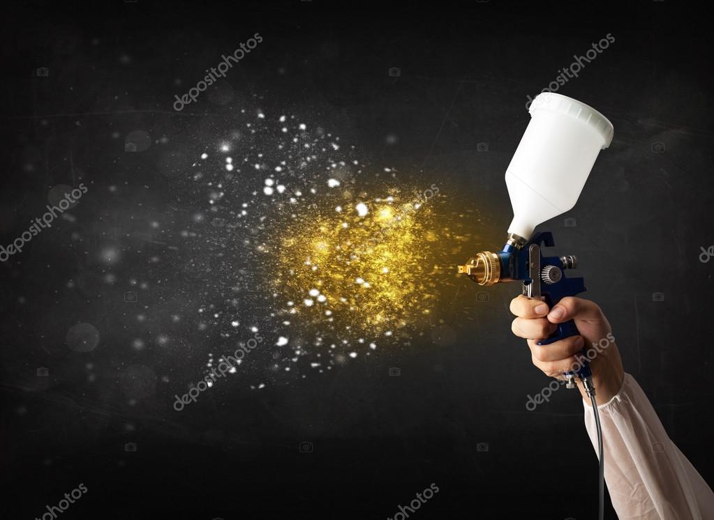 Worker with airbrush painting with glowing golden paint — Stock Photo