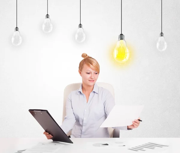 Zakelijke vrouw zit aan tafel met idee gloeilampen — Stockfoto