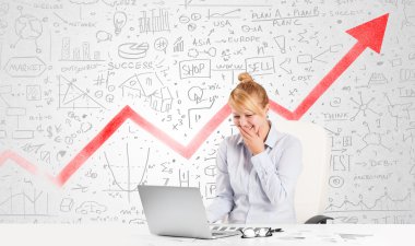 Piyasa diyagramlarıyla masada oturan iş kadını.