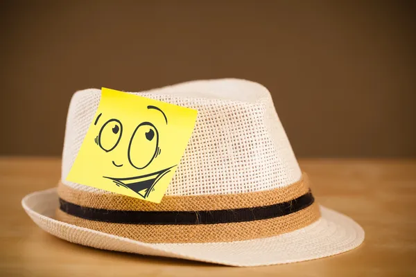 Post-it con faccina sorridente incollata sul cappello — Foto Stock