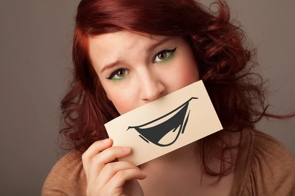 Happy cute girl holding paper with funny smiley drawing — Stock Photo, Image