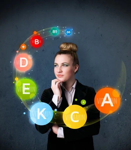 Young woman thinking with vitamins circulation around her head — Stock Photo, Image