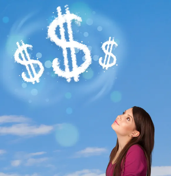 Young girl pointing at dollar sign clouds on blue sky — Stock Photo, Image